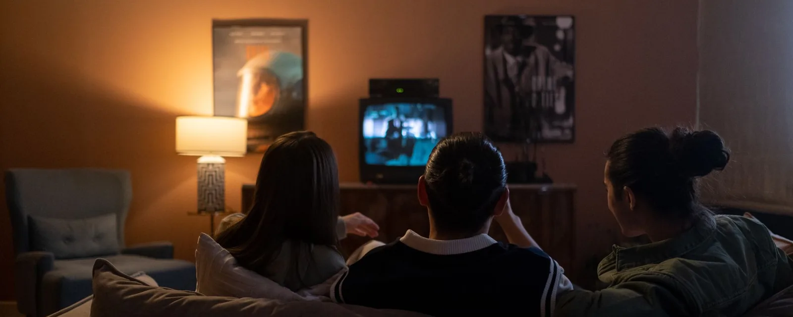 Três amigos no sofá assistindo TV durante o teste IPTV grátis à noite